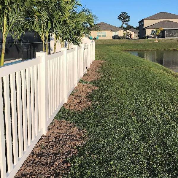 Installed tan vinyl semi-privacy picket fence along a residential lakefront property line in Tampa
